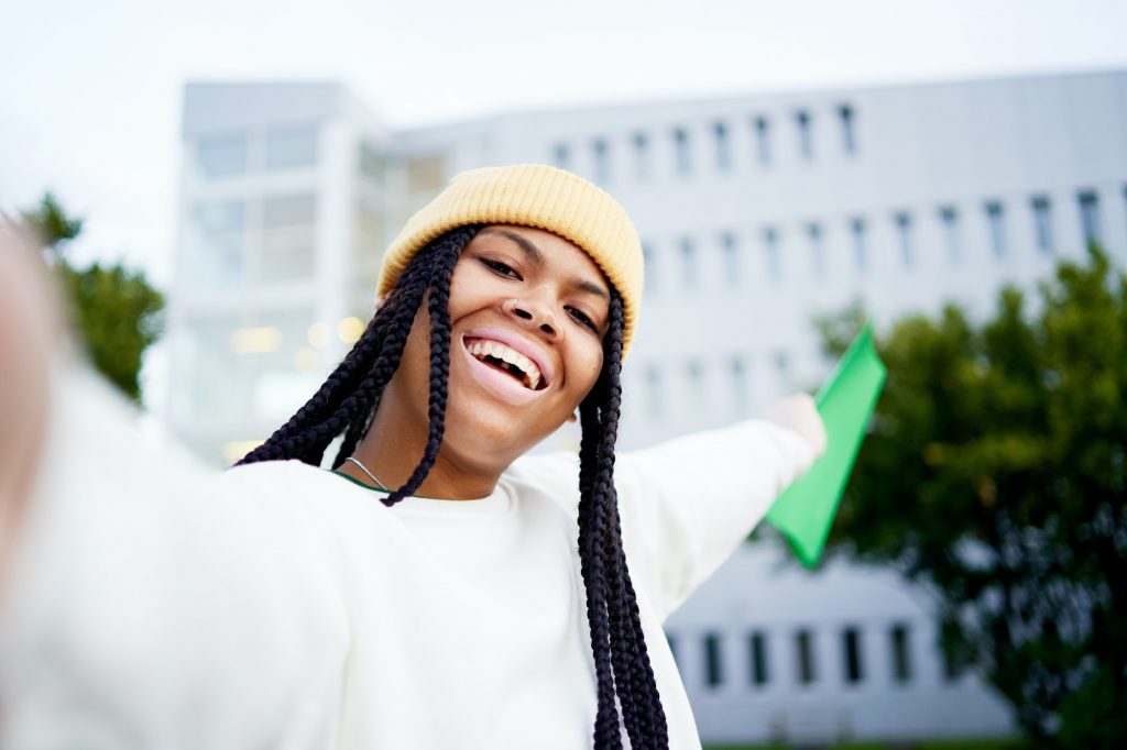 Cool african student open arms in celebration in front of the university